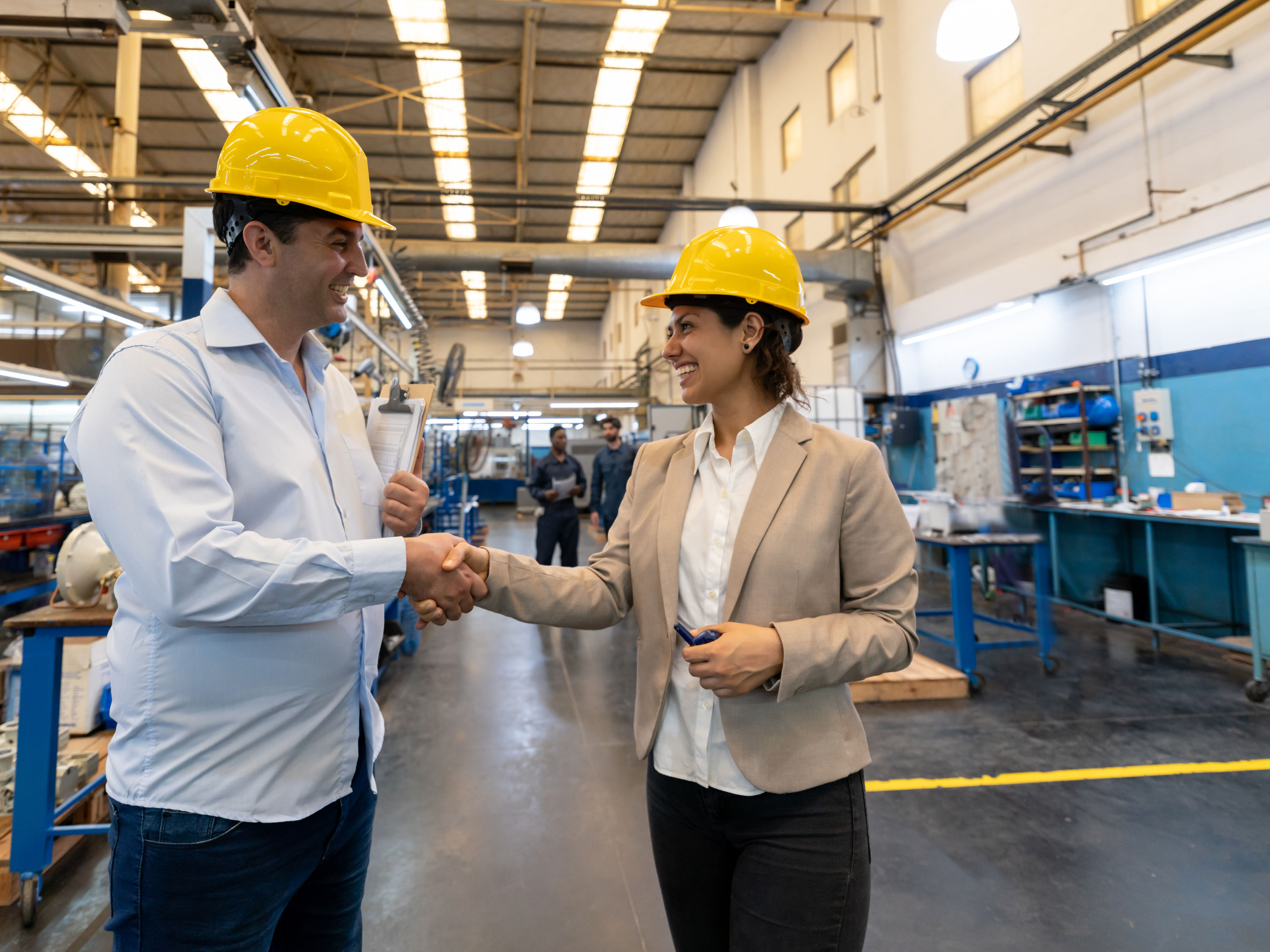 Two colleagues shaking hands at a factory.