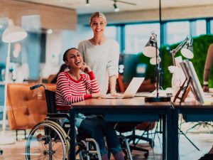 Businesswoman in a wheelchair working in a creative office. Business team in modern coworking office space.